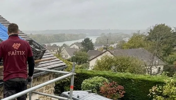 Couvreur Faîtix sur un toit de Poissy, vue sur la vallée de la Seine et les pavillons voisins